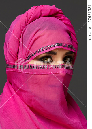 Close-up shot of a young charming woman wearing the pink hijab decorated with sequins. Arabic style. Close-up shot of a young charming woman wearing the pink hijab decorated with sequins. Arabic style. 97621581
