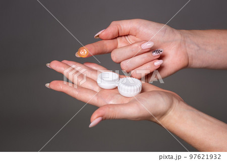 Contact eye lens. Close-up of woman hands holding white eyelense container. Contact eye lens. Close-up of woman hands holding white eyelense container. 97621932