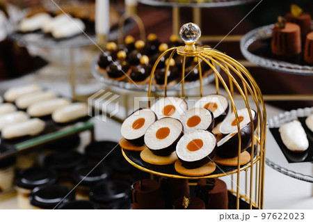 Many cakes standing among the candy bar. Sweet table. Banquet table. Holiday food and sweet festive table. 97622023