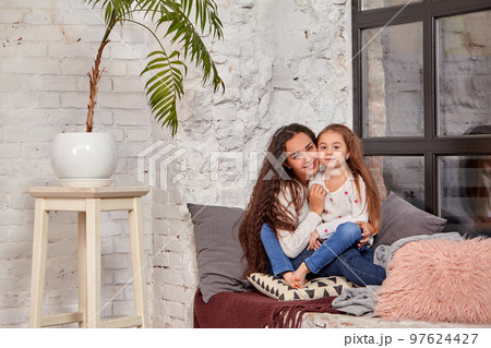 Mother and daughter sitting on sill near window in room Mother and daughter sitting on sill near window in room 97624427