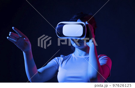 Brunette girl wearing virtual reality goggles at home. Gaming, remote education, online education, indoor lifestyle. 97626125