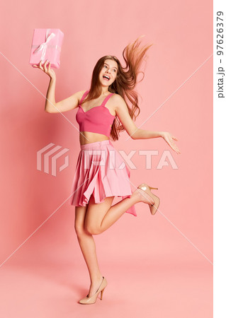 Portrait of beautiful young girl in cute costume posing with present box over pink background. Party gifts Portrait of beautiful young girl in cute costume posing with present box over pink background. Party gifts 97626379