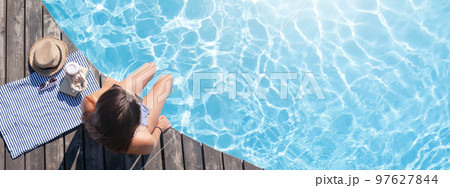 Woman on wooden deck near swimming pool 97627844