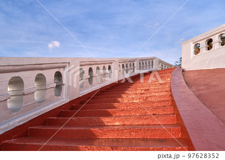Red sunlit stairs and white banisters at blue sky. Concept, ascension Red sunlit stairs and white banisters at blue sky. Concept, ascension 97628352