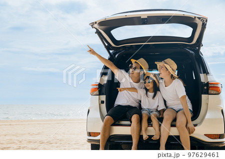 Family Day. Father, Mother and daughter enjoying road trip sitting on back car and point finger out blue sky, Happy people having fun in summer vacation on beach, Family travel in holiday at sea beach Family Day. Father, Mother and daughter enjoying road trip sitting on back car and point finger out blue sky, Happy people having fun in summer vacation on beach, Family travel in holiday at sea beach 97629461