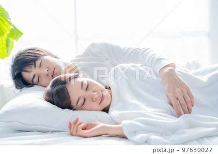 寝室のベッドで眠る若い夫婦-朝 97630027