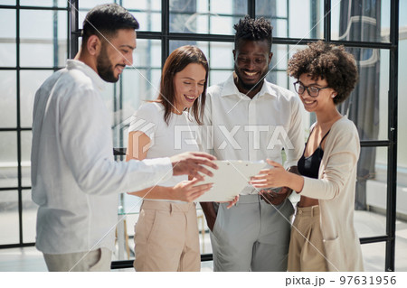 Employees working at computer together, discussing content 97631956