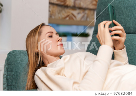 Young adult woman work with smartphone on the couch. Work from home concept 97632084