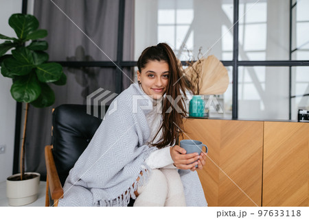 Sweet woman relaxing with hot beverage covered blanket 97633118