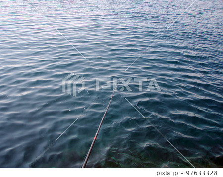 穏やかな海面と沖へと伸びる磯釣り用の竿の穂先の風景画像。 穏やかな海面と沖へと伸びる磯釣り用の竿の穂先の風景画像。 97633328