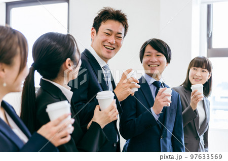 コーヒーを飲みながら充実した笑顔で談笑するビジネスマンとビジネスウーマン（アジア人・日本人の男女） 97633569