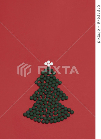 Red background, mockup for medicine, Christmas tree made of green white pills, tablets,vitamins spirulina. Merry Christmas, Happy New Year concept, pharmacy postcard,flatly, top view, copy space 97635355