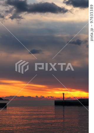 漁港のオレンジ色の夕焼けとシルエット 97635389
