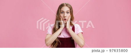Cute feminine teenage girl in trendy overalls with tattoo on arm folding lips in wow, touching cheeks from amazement and surprise staring at camear shocked and astonished from awesome sales Cute feminine teenage girl in trendy overalls with tattoo on arm folding lips in wow, touching cheeks from amazement and surprise staring at camear shocked and astonished from awesome sales 97635800