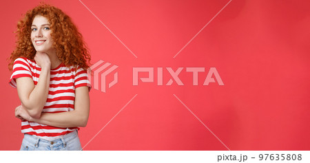 Cheerful lively cute tender redhead curly girl romantic summer mood pondering what present girlfriend happy pride month silly smiling touch face-line look curious camera red background 97635808