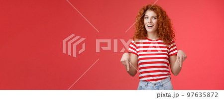 Hey check it out friend. Sassy good-looking cheeky redhead stylish girlfriend curly hairstyle wear summer t-shirt pointing down index finger smiling amused delighted present awesome recommendation 97635872