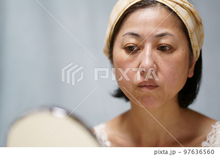 鏡を見るシミシワのある中年女性 97636560