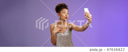 Stylish silly feminine african-american woman partying in silver stylish dress folding lips mwah gesture posing selfie taking photo during party night club looking flirty display camera 97636822