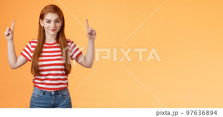 Cute lovely redhead girlfriend hint boyfriend what buy anniversary, pointing copy space promo, indicate fingers up, look camera assured, determined get what want, stand orange background 97636894