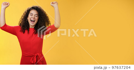 Oh yeah I am winner, on top of world. Excited ambitious and happy young successful busiensswoman getting promotion yelling yes with broad smile and closed eyes lifting hands in triumph and celebration 97637204