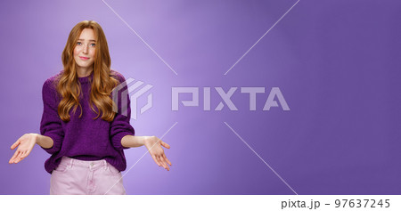 Who cares chill I not know. Portrait of clueless and unbothered cute redhead female in purple sweater smirking in sorry and shrugging with hands sideways being questioned and puzzled to answer Who cares chill I not know. Portrait of clueless and unbothered cute redhead female in purple sweater smirking in sorry and shrugging with hands sideways being questioned and puzzled to answer 97637245