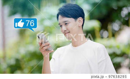 外でスマートフォンを操作する若い男性 97638293