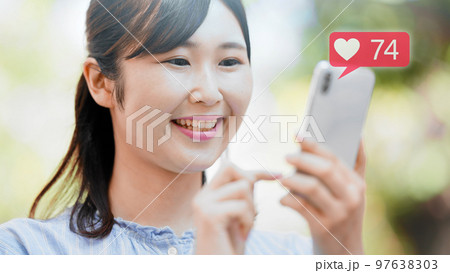 屋外でスマートフォンを操作する若い女性 屋外でスマートフォンを操作する若い女性 97638303
