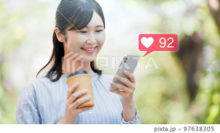屋外でスマートフォンを操作する若い女性 屋外でスマートフォンを操作する若い女性 97638305