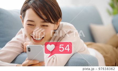 ソファーでスマートフォンを操作をする若い女性 97638362