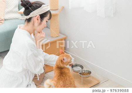 猫に餌をあげる飼い主のアジア人女性 97639088