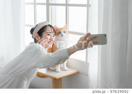 愛猫と一緒にスマホで写真を撮るアジア人女性 97639092