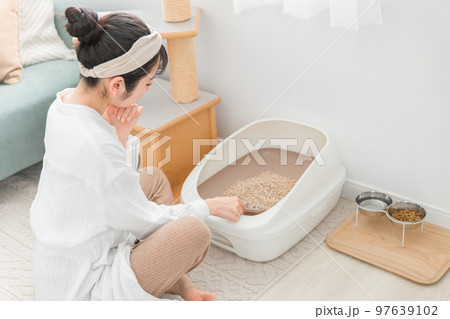 猫用トイレの猫砂を掃除するアジア人女性 97639102