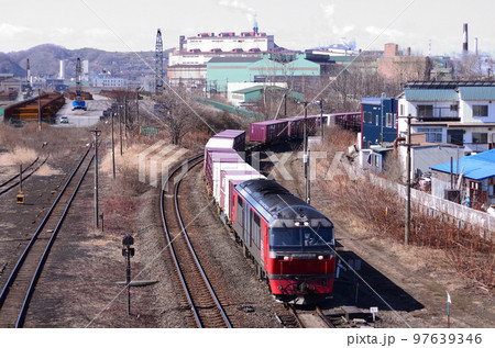 室蘭を代表する製鉄所をバックに函館方から東室蘭駅に進入する下り貨物列車 97639346