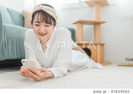 家でくつろぎながらスマホを見るアジア人女性（猫好き） 97639562