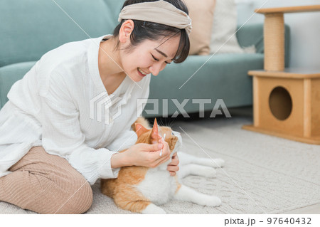 綿棒を使って猫の耳掃除をする飼い主のアジア人女性 97640432