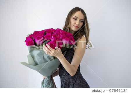 Beautiful woman in black dress holding bouquet of pink flowers and roses smiling happily on white background 97642184
