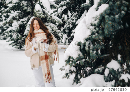 Portrait of a girl with long hair in mittens in a winter forest . Snowy winter Portrait of a girl with long hair in mittens in a winter forest . Snowy winter 97642830