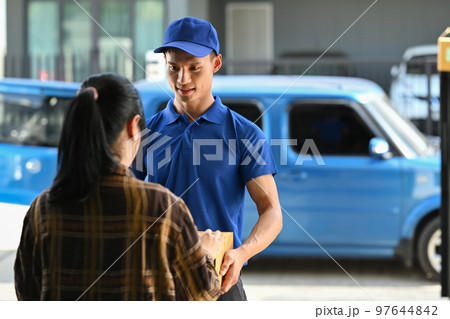 Friendly delivery man giving a cardboard box to woman customer at home. Delivery service, delivery home and shipping concept Friendly delivery man giving a cardboard box to woman customer at home. Delivery service, delivery home and shipping concept 97644842