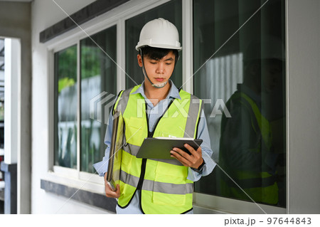 Image of engineer man looking at clipping board and checking building construction progress, working at construction site Image of engineer man looking at clipping board and checking building construction progress, working at construction site 97644843