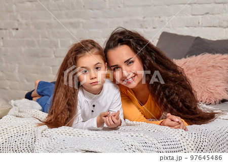 Love of young mother and daughter. They lie on the bed at home and have fun Love of young mother and daughter. They lie on the bed at home and have fun 97645486