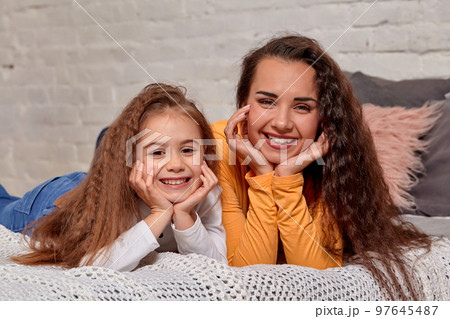 Love of young mother and daughter. They lie on the bed at home and have fun 97645487