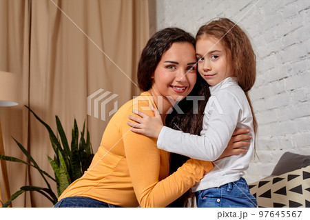 Love of young mother and daughter. They sit on the bed at home and have fun 97645567
