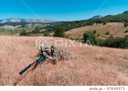 Army soldier holding sniper rifle with scope and aiming in forest. War, army, technology and people concept Army soldier holding sniper rifle with scope and aiming in forest. War, army, technology and people concept 97649373