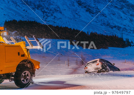 The roadside assistance service pulling the car out of the canal. An incident on a frozen Scandinavian road. 97649797