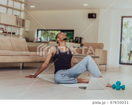 Training At Home. Sporty man doing training while watching online tutorial on laptop, exercising in living room, free space Training At Home. Sporty man doing training while watching online tutorial on laptop, exercising in living room, free space 97650031