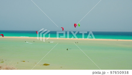 Free kiters on the ocean waves. Kitesurfing in the shallow blue transparent water. Paradise island. Sport activity. Large group of athletes. Free kiters on the ocean waves. Kitesurfing in the shallow blue transparent water. Paradise island. Sport activity. Large group of athletes. 97650938