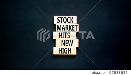 Stock market hits new high symbol. Concept words Stock market hits new high on wooden blocks on a beautiful black table black background. Business and stock market hits new high concept. Copy space. 97653636