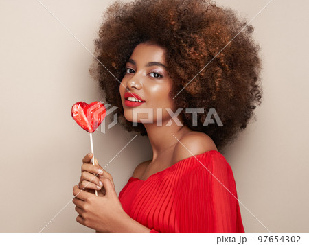 Beautiful portrait of an African girl with a heart shaped lollipop 97654302