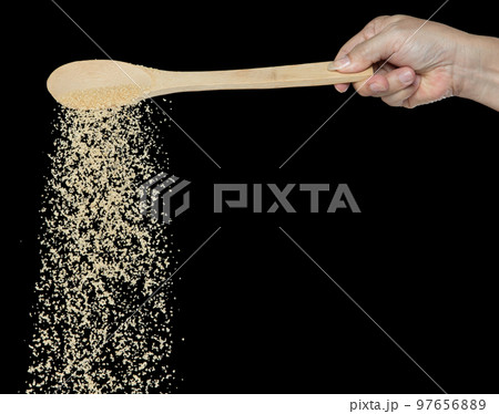 Brown Sugar fall, brown grain sugar pouring down abstract cloud fly from wooden spoon. Beautiful complete seed sugarcane, food object design. Selective focus freeze shot Black background isolated 97656889