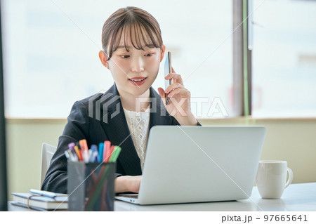 デスクで電話をする若い女性 97665641